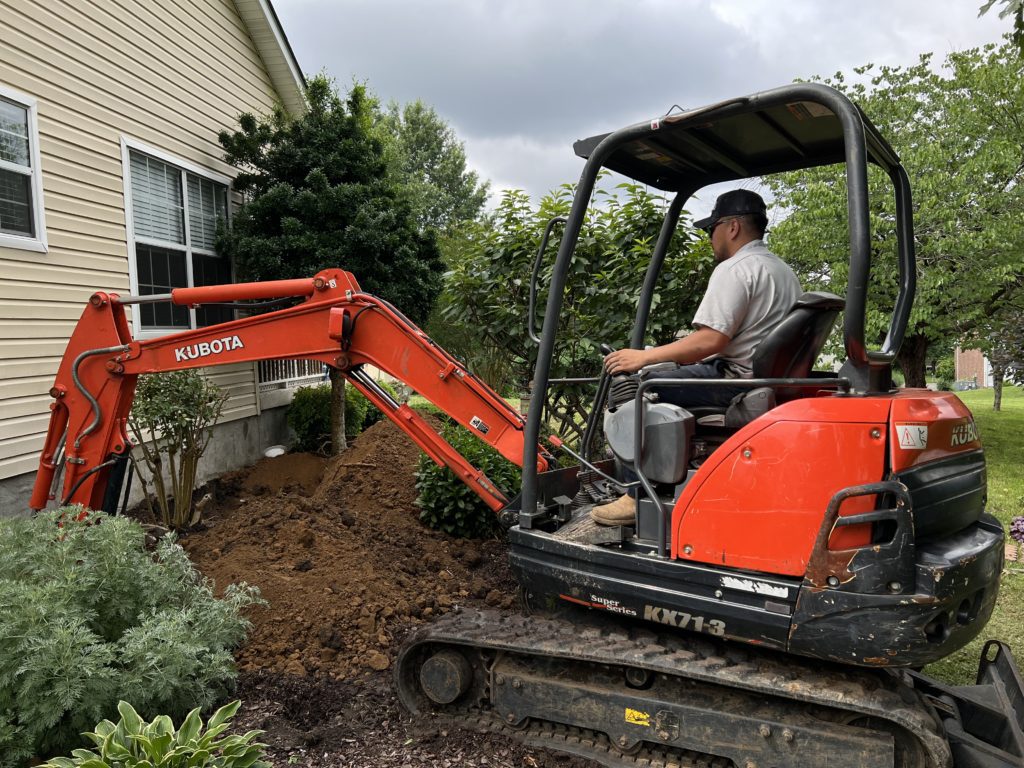 TFS worker operating an orange Kubota