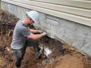 Worker digging under home foundation 